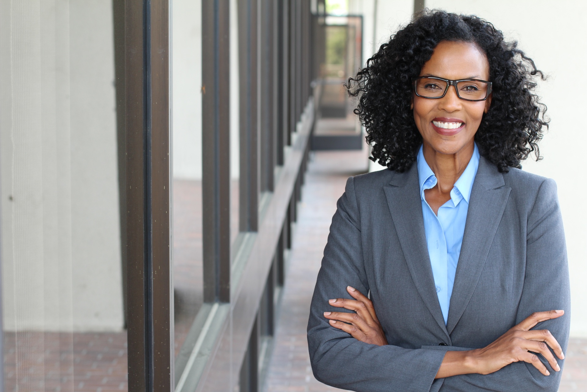 Confident businesswoman in glasses smiling with arms crossed in a suit